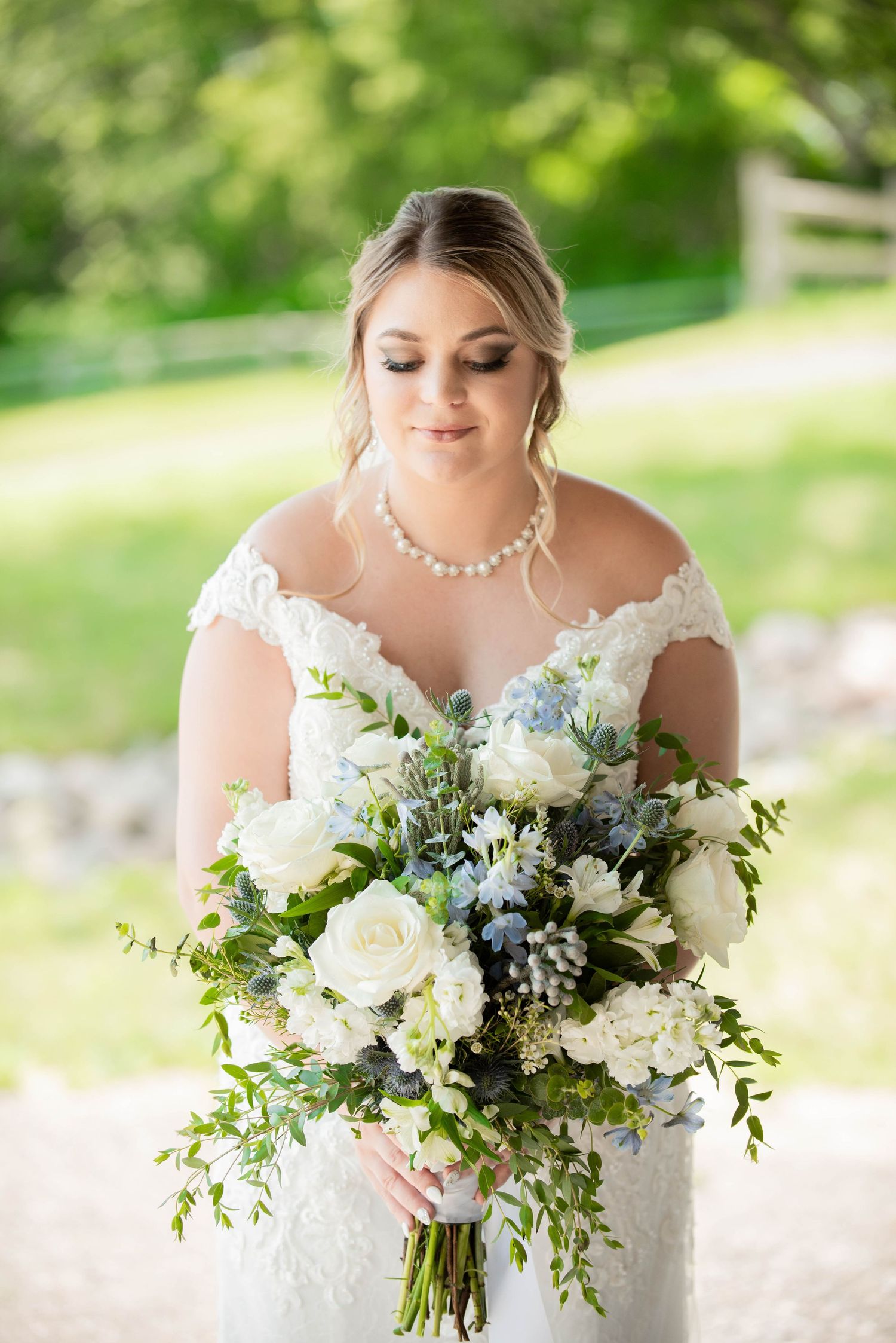 Elegant white and blue wedding bouquet with roses and greenery against natural backdrop. Zimmerman MN Weddings