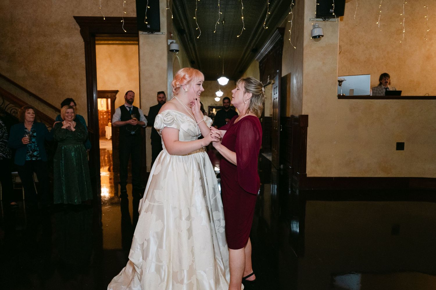 Central MN Wedding Photos | Bride in ivory gown sharing tender moment with guest in burgundy dress.
