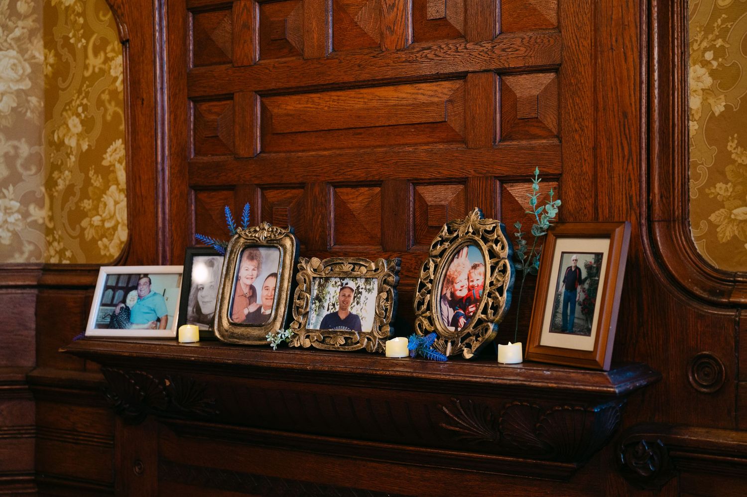 Central MN Wedding Photos | Framed family photos displayed on a wooden mantle at a wedding reception.
