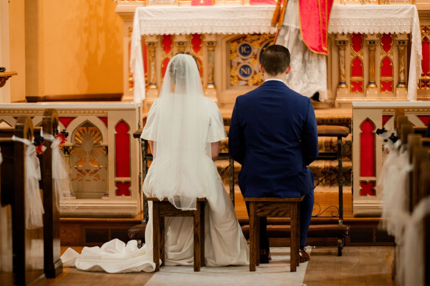 Traditional church altar decorated with red and white accents for a wedding ceremony.