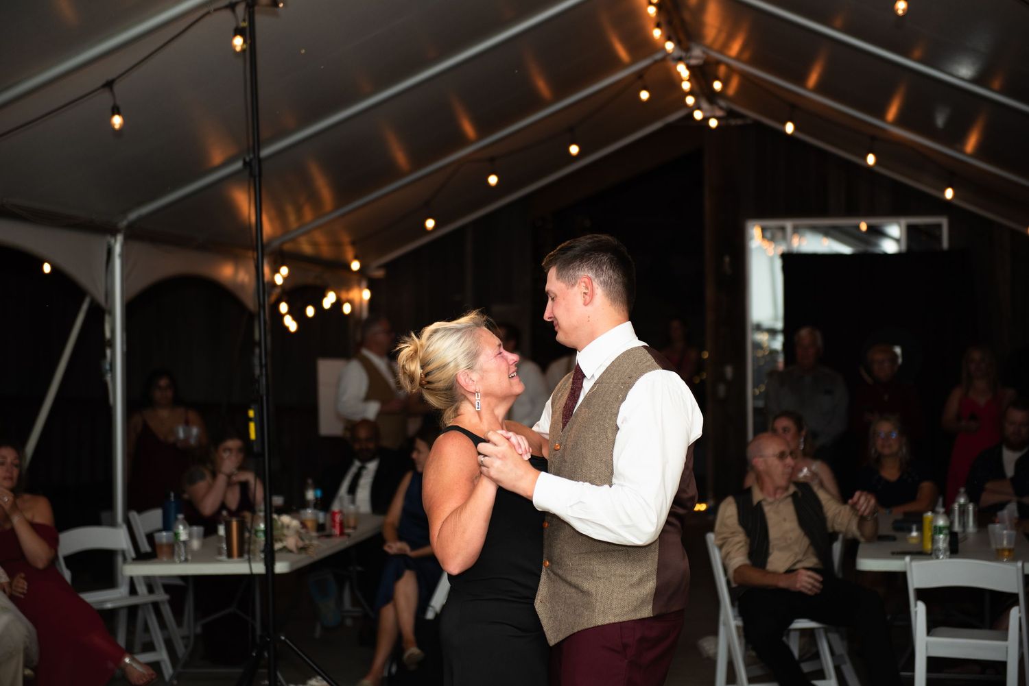 Dancing couples enjoy themselves on the dance floor at an outdoor tented wedding reception.