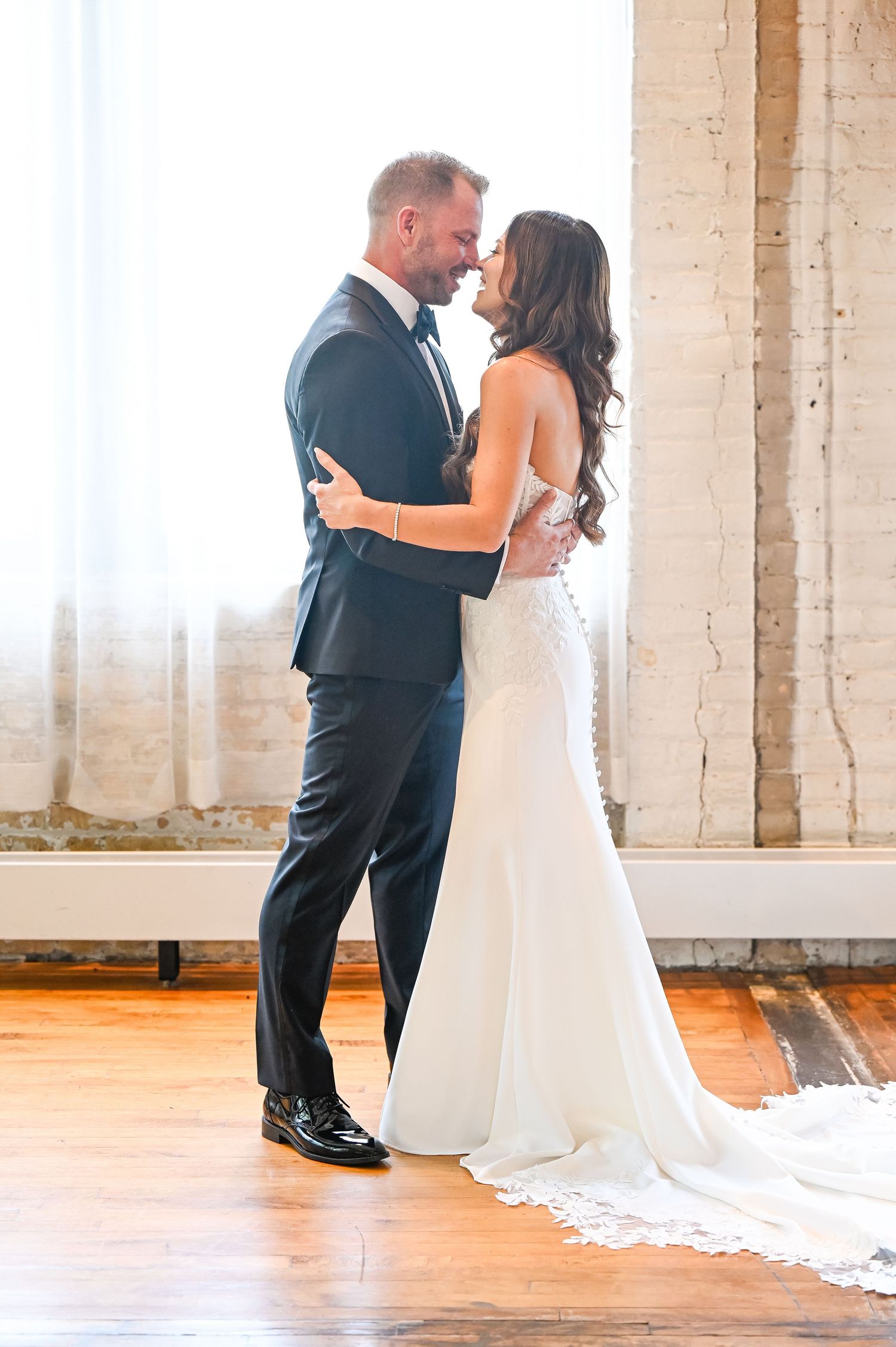 Couple shares their first look moment in a bright industrial space with white brick columns.