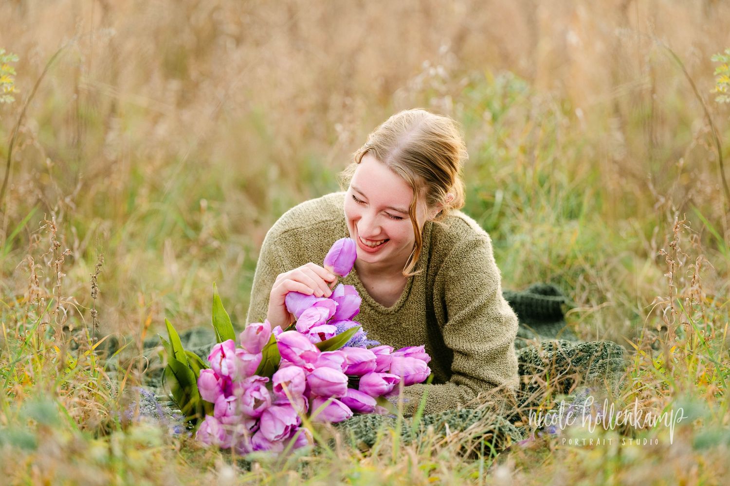 Person holding vibrant pink orchid flowers while sitting in a golden autumn field Senior session in Central MN.