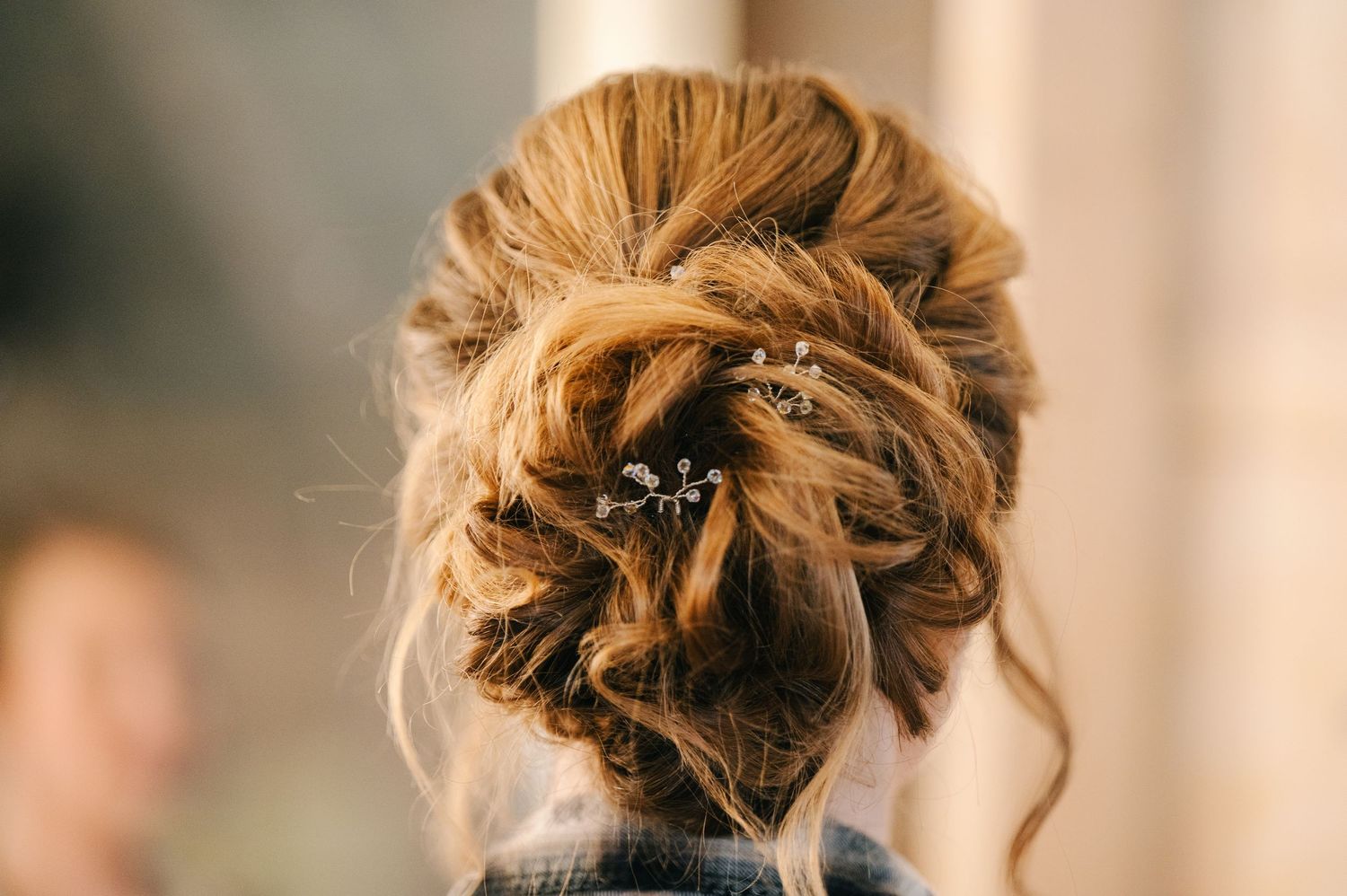 Elegant bridal updo hairstyle with twisted bun and delicate crystal hair pin accessory, back view.