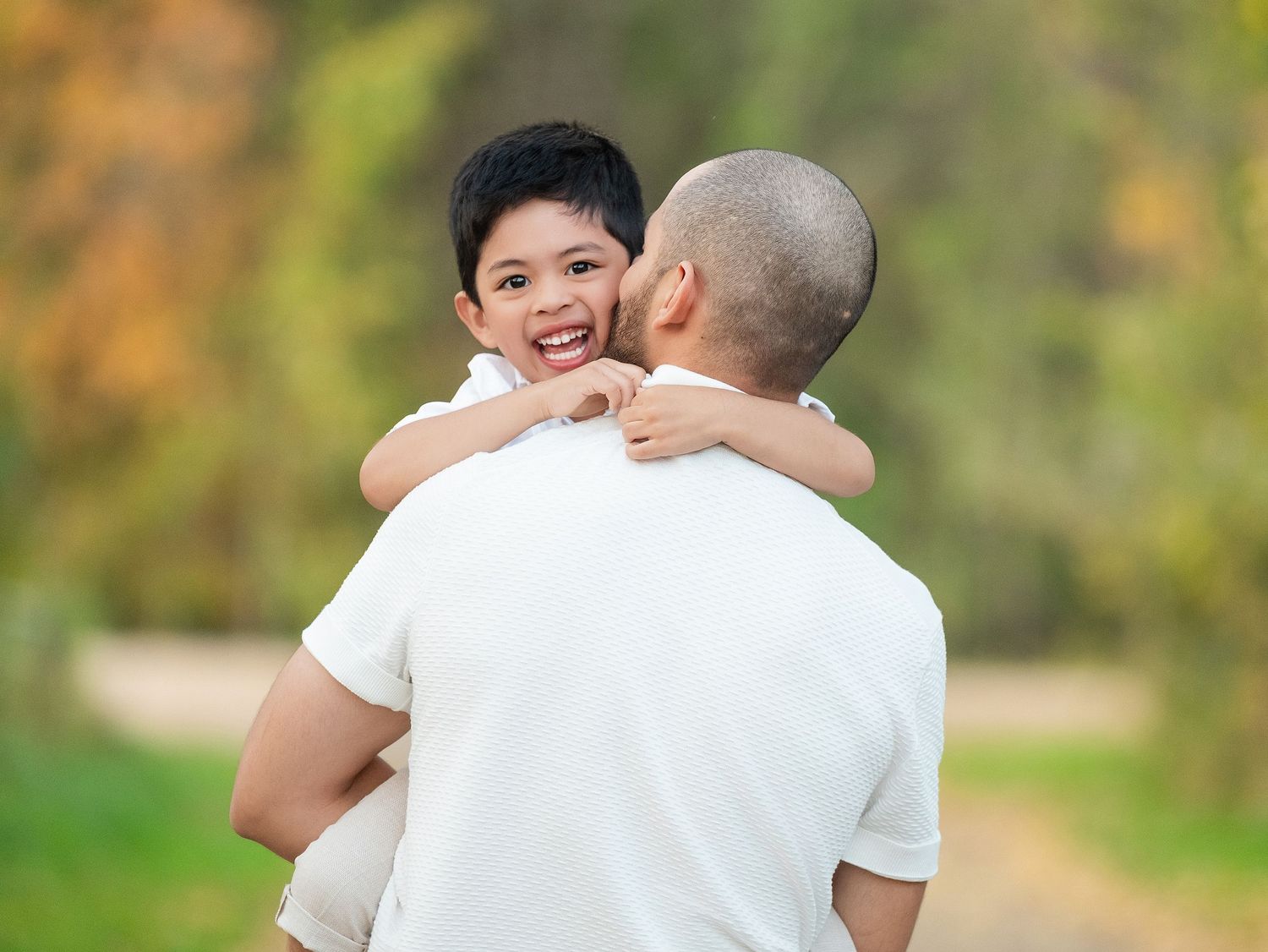 A joyful moment of affection and laughter captured between parent and child on an autumn nature trail.