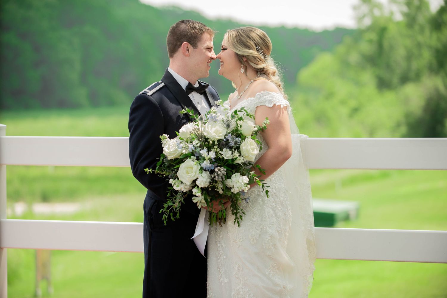 Wedding couple in formal attire embracing on a lush green countryside balcony. Zimmerman MN Weddings