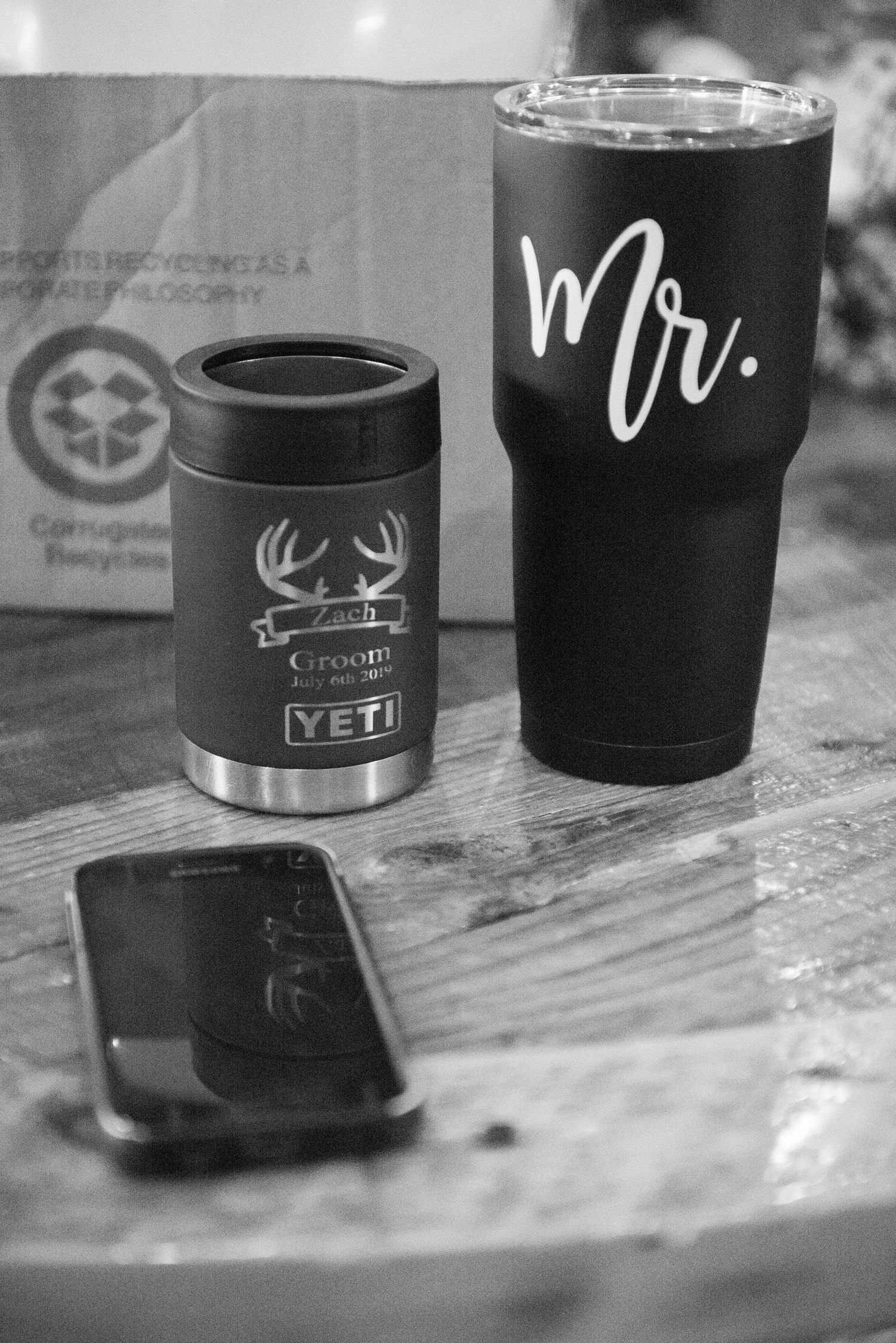 Black and white photo of YETI tumblers and other drink containers arranged on a rustic wooden surface. Zimmerman MN Weddings