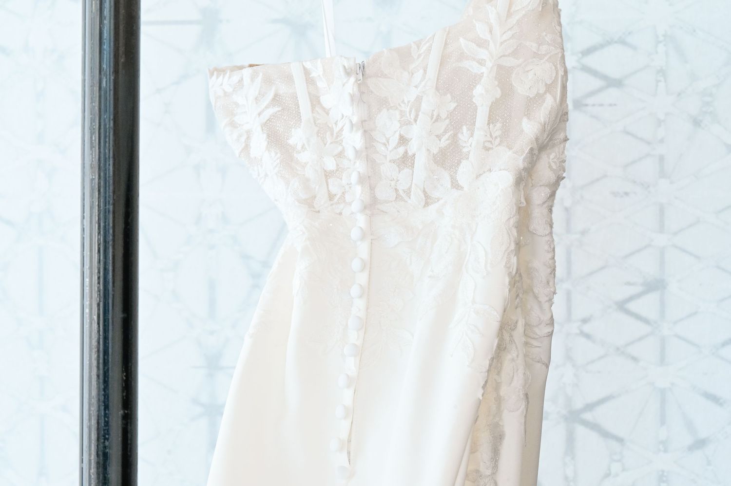 Close-up detail of a white wedding dress bodice with intricate button detailing.