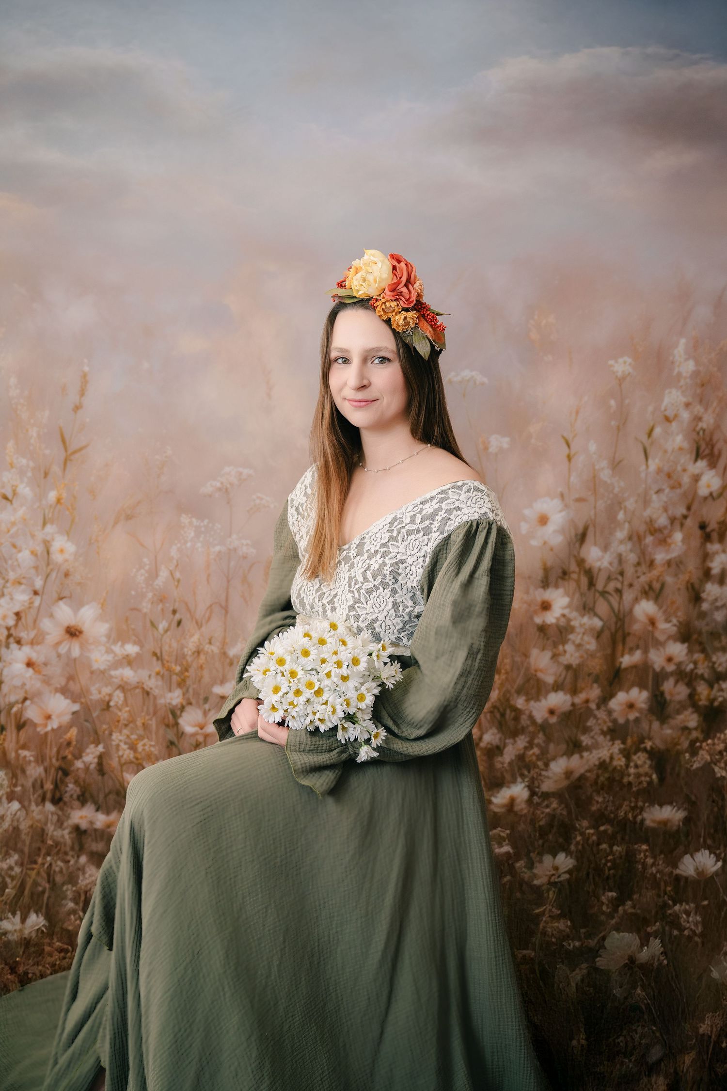 Woman in green dress with floral crown holds white daisies, posed against a dreamy floral field backdrop. mother day photoshoot