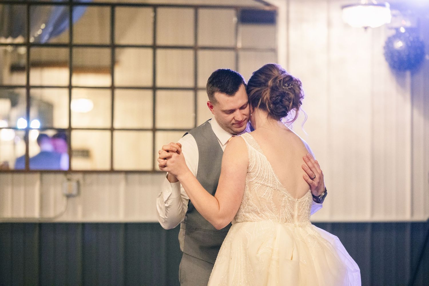 Bride and groom sharing intimate first dance at softly lit wedding reception.
