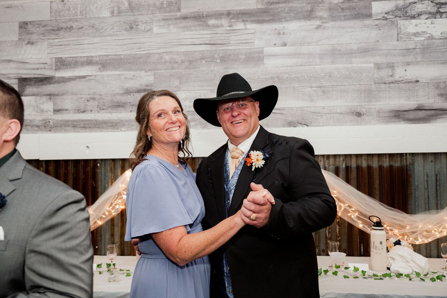 A special dance moment captured at a wedding reception with rustic wood panel backdrop.