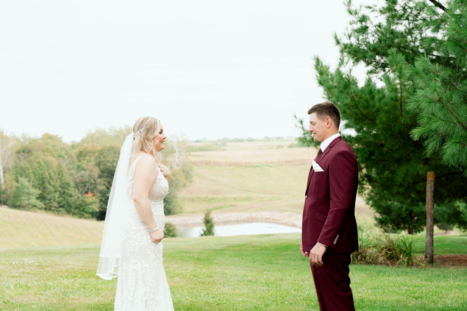 A couple shares their first look moment outdoors on their wedding day against a scenic autumn landscape.