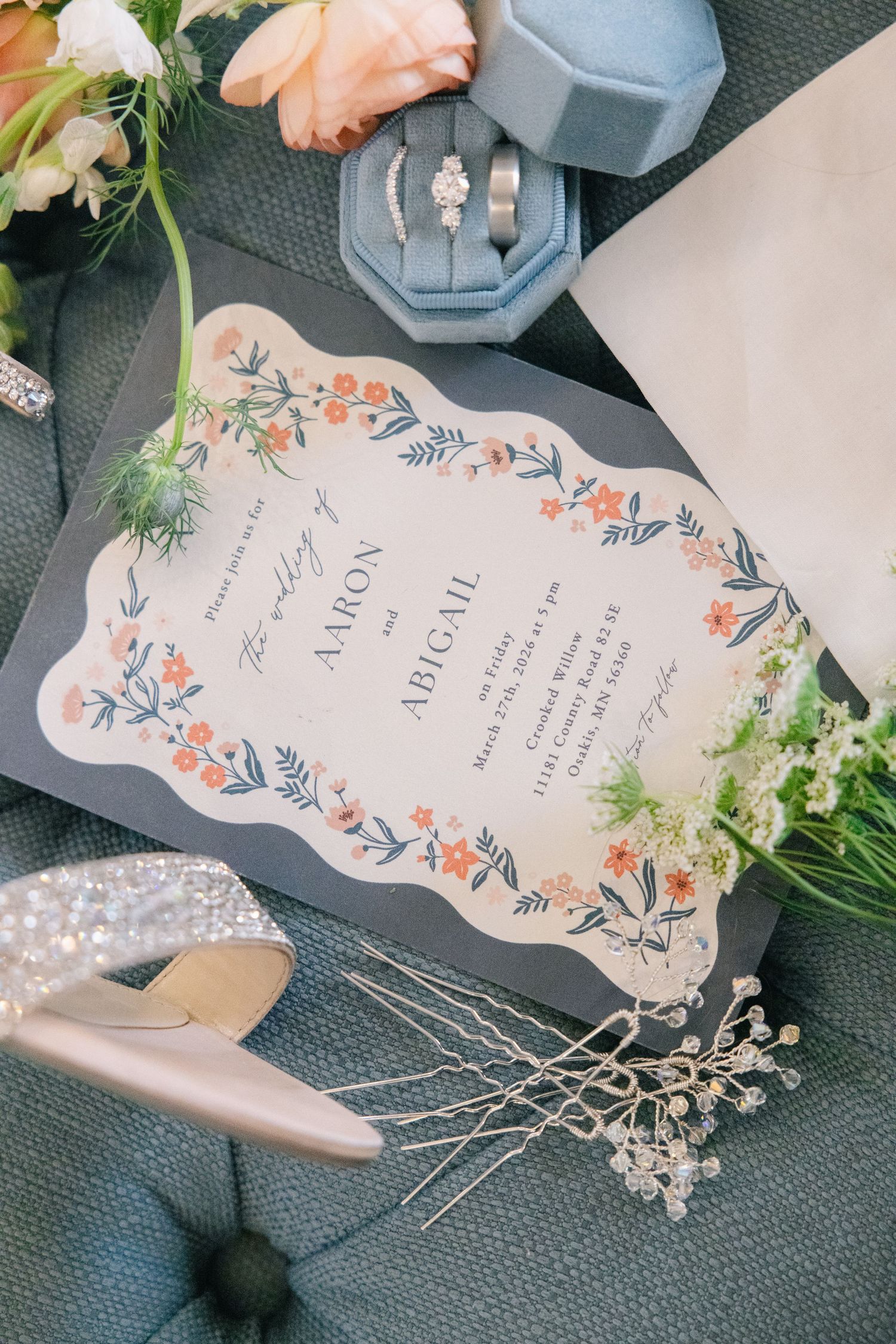 Elegant wedding invitation with floral border for Aaron and Abigail, surrounded by rings, shoes, and flowers.