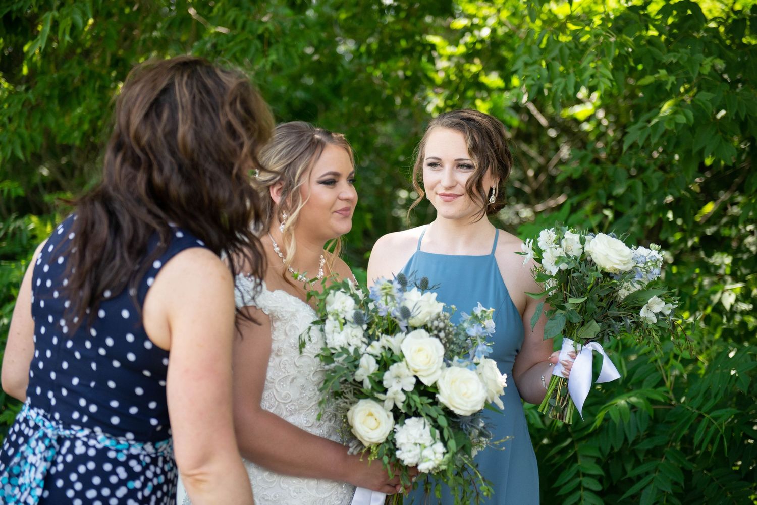 Wedding party gathered outdoors with white floral bouquets. Zimmerman MN Weddings