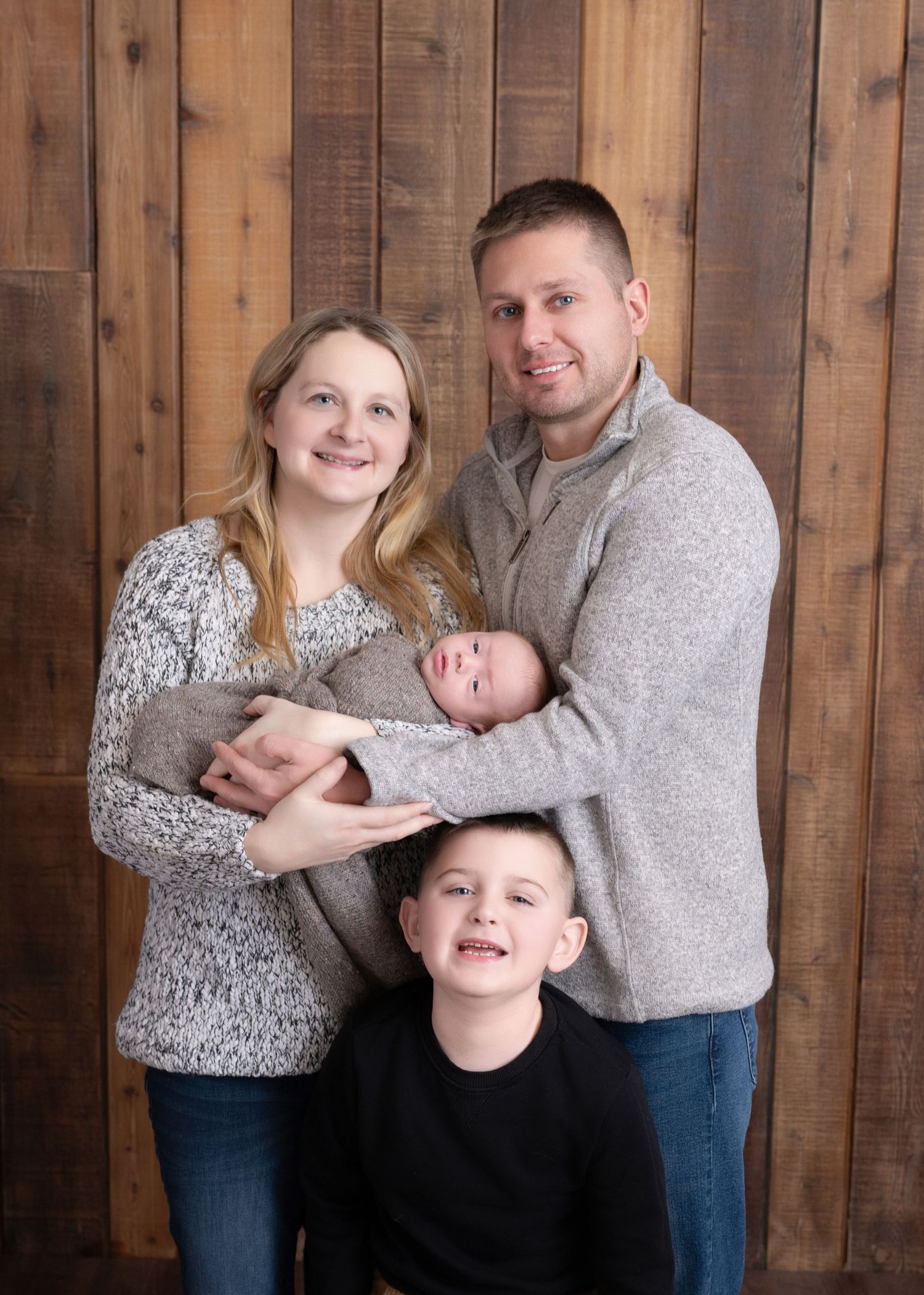 A family portrait with rustic wooden paneling background.
