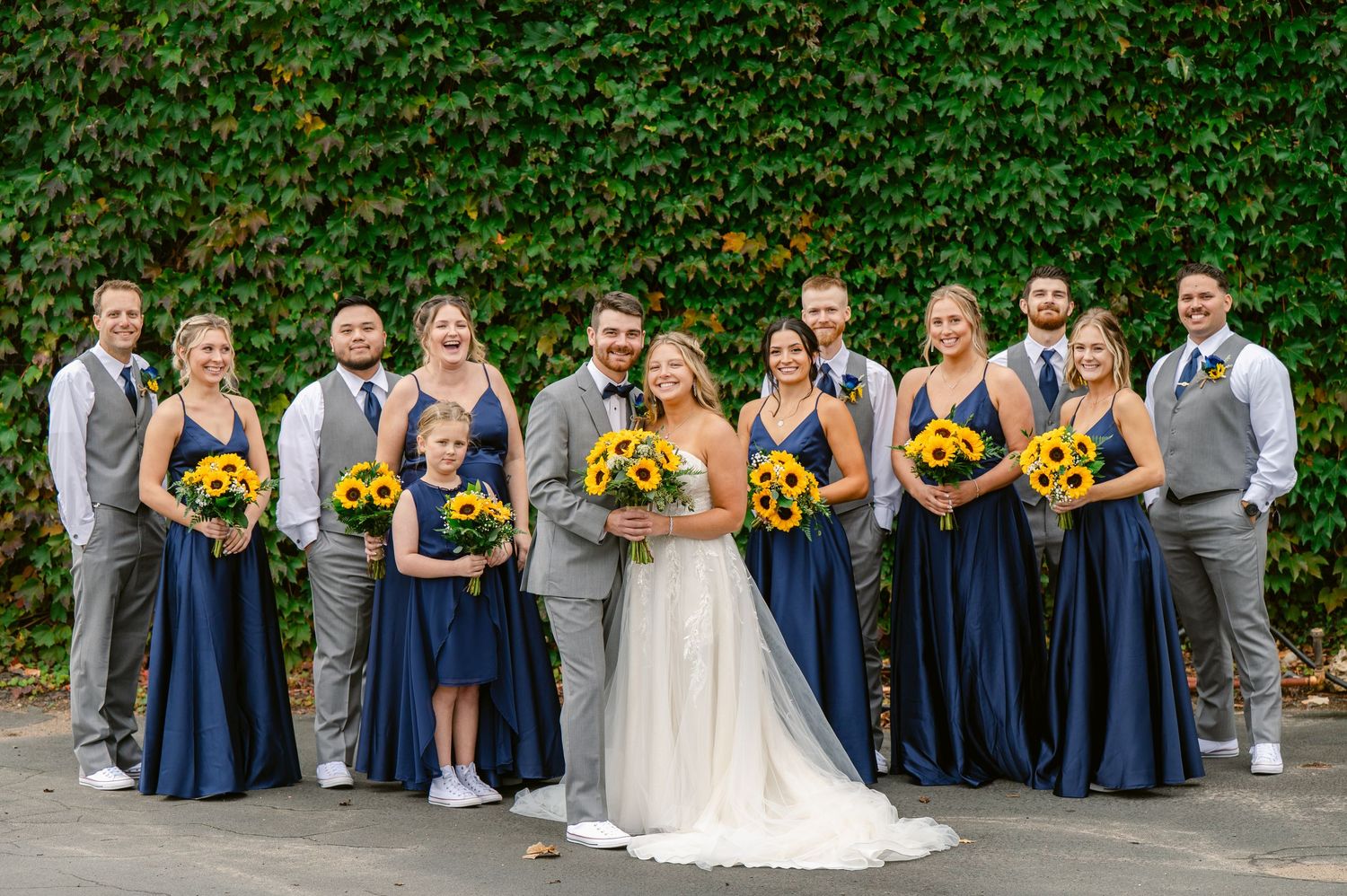 Central MN Wedding Photos | Full wedding party portrait with bride, groom, bridesmaids and groomsmen by ivy wall.