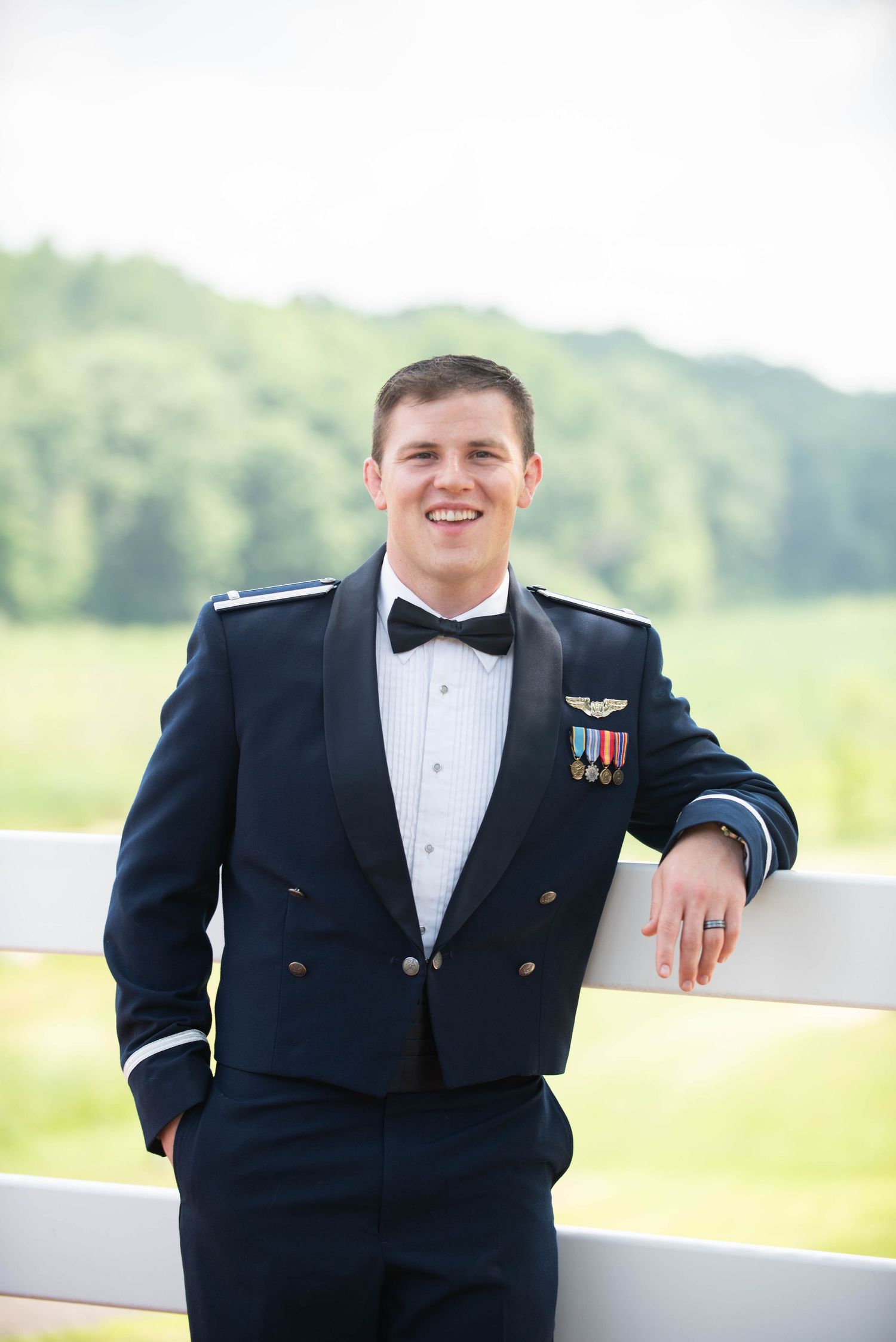 Military groom in formal dress uniform poses against outdoor backdrop. Zimmerman MN Weddings