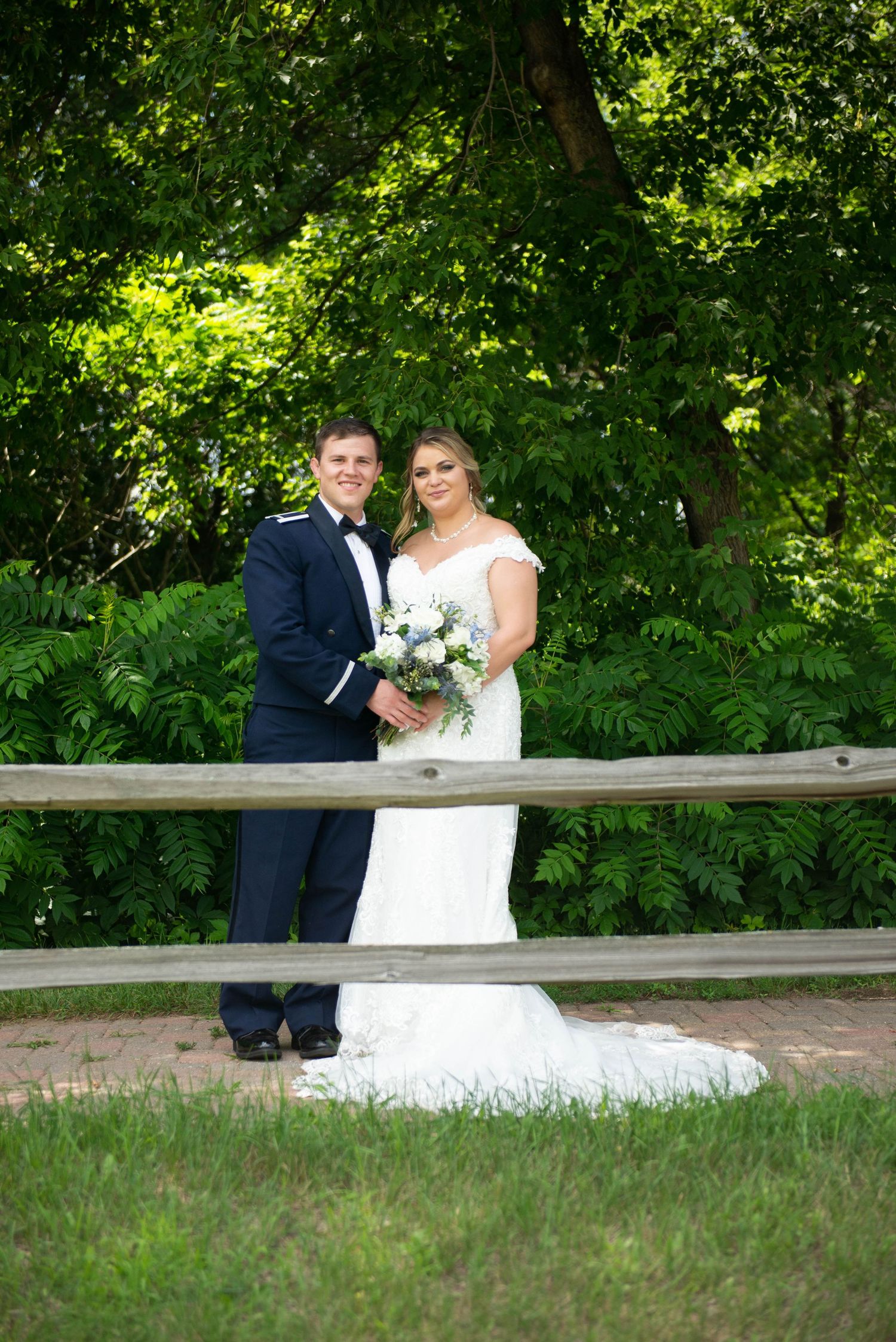 Wedding couple sitting together on a wooden bench in a garden setting. Zimmerman MN Weddings