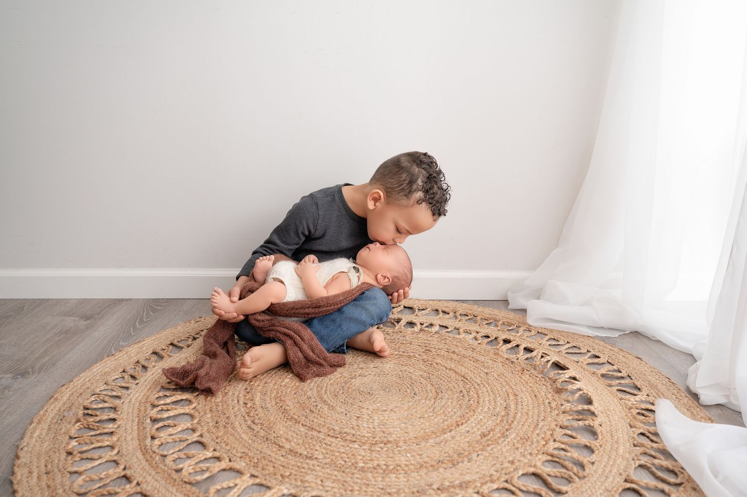A person lies on a circular jute rug while arranging its fringe tassels in a spiral pattern.