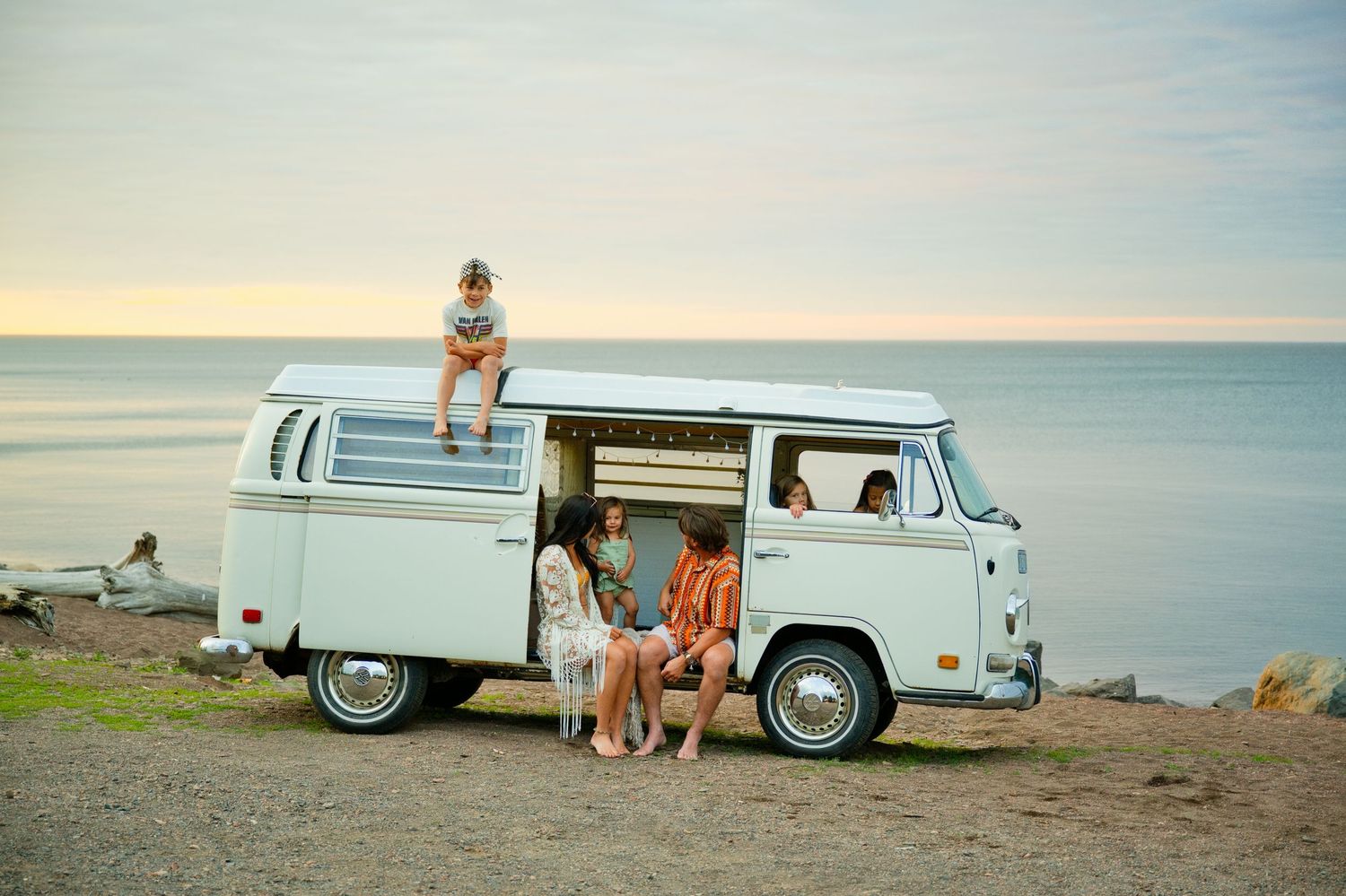 Adorable family relaxing in a vintage VW camper van parked on a Lake Superior beach at sunrise. Grand Marais Minnesota Family Photos