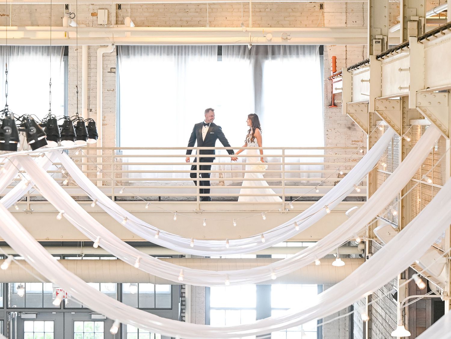 Couple photographed on a modern white staircase in an industrial-style wedding venue.