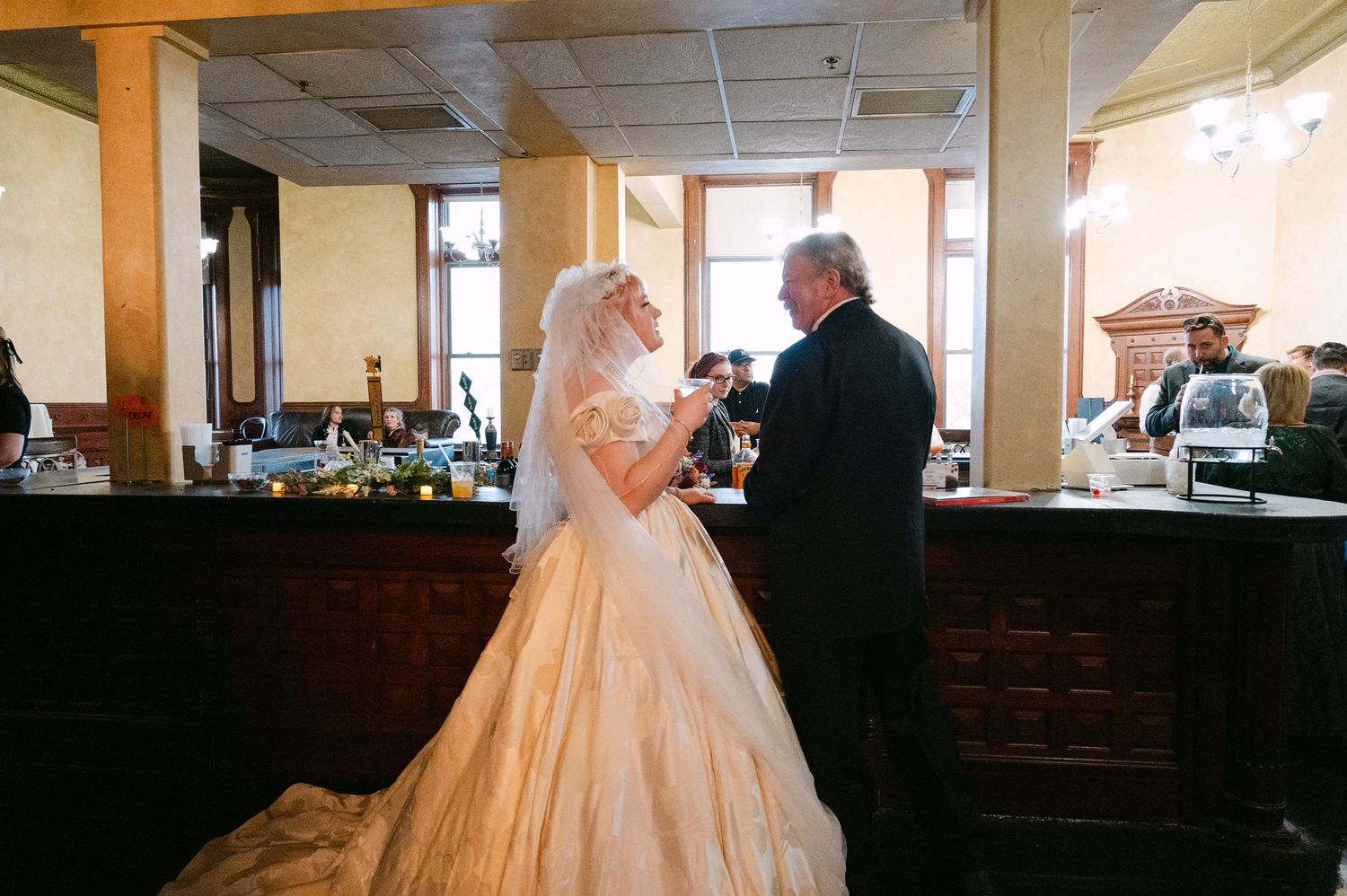 Central MN Wedding Photos | Bride in elegant white ball gown with veil stands with groom at wedding venue bar ceremony.