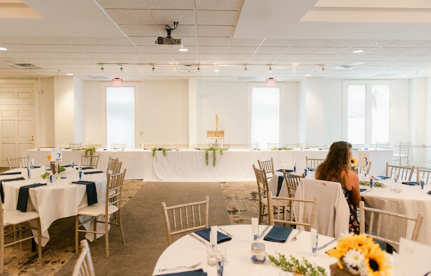Central MN Wedding Photos | Elegant wedding reception room with white tablecloths, navy accents, and chiavari chairs.