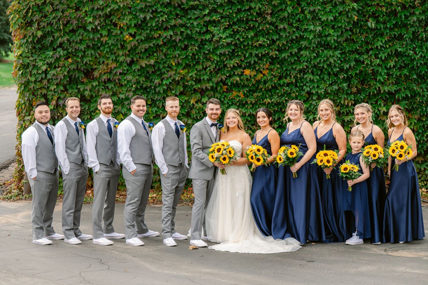 Central MN Wedding Photos | Wedding party in gray suits and navy dresses holding sunflower bouquets.