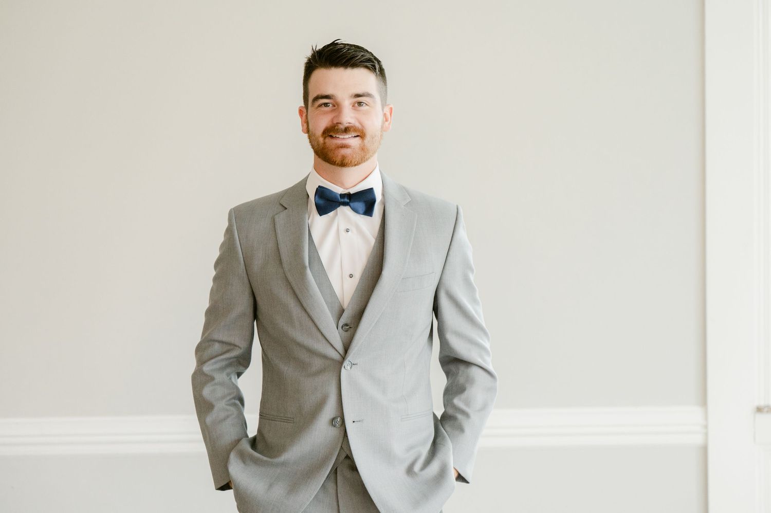 Central MN Wedding Photos | Handsome groom smiling in gray three-piece suit with navy bow tie.