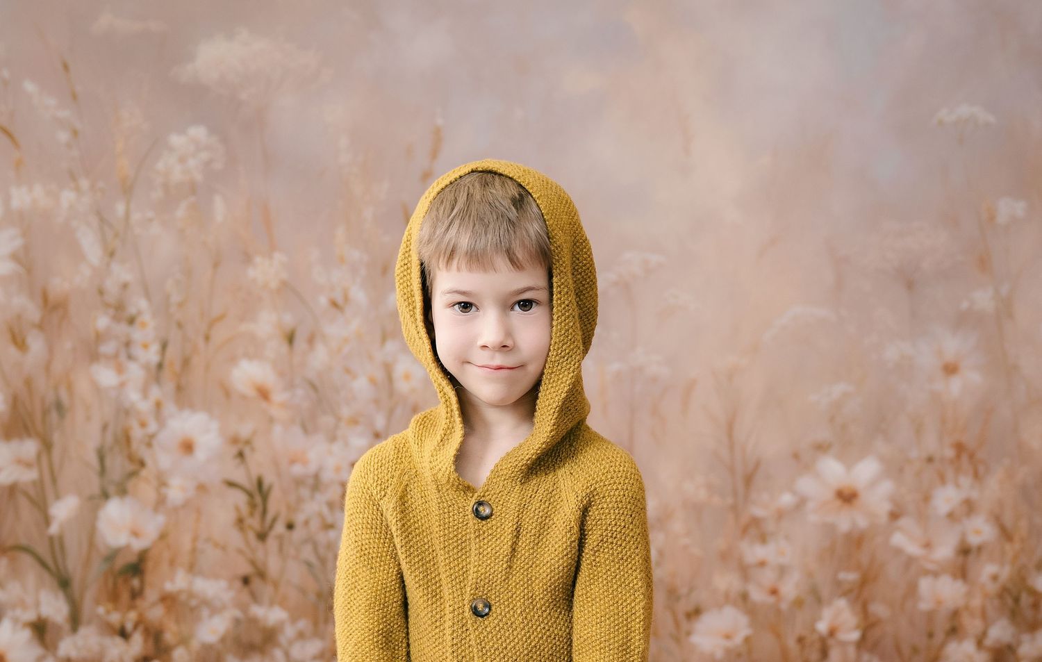 A sequence of photos showing a boy in a mustard yellow hooded coat against a whimsical flower wall.