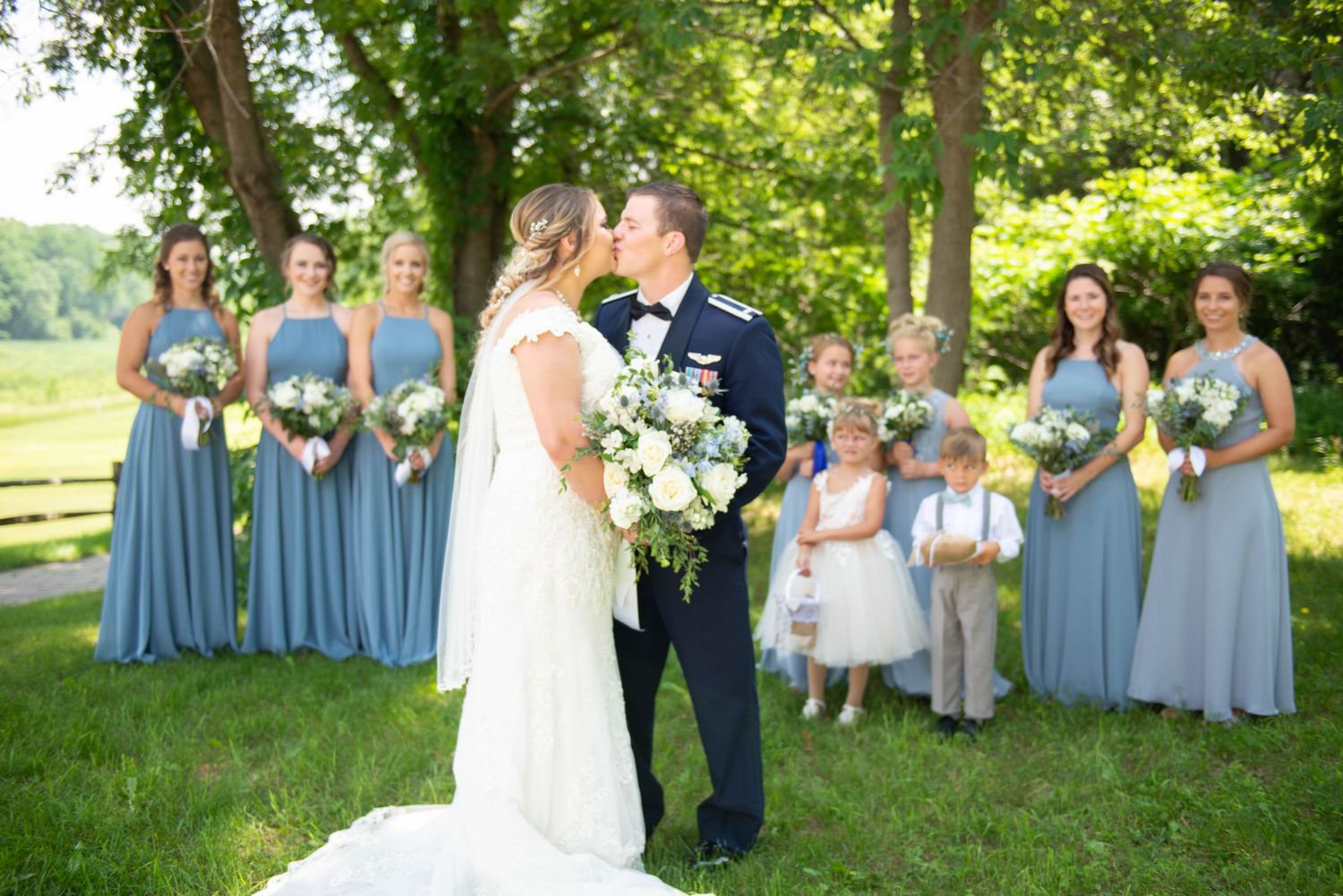 Outdoor wedding ceremony with bridal party in powder blue dresses gathered on lush green lawn. Zimmerman MN Weddings