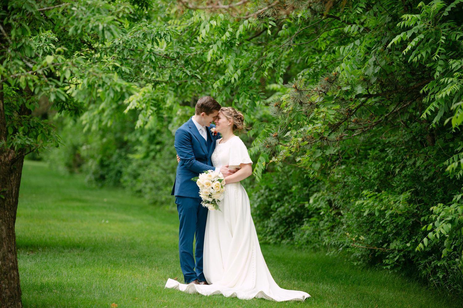 A couple shares an intimate moment in a serene garden setting during their wedding day.