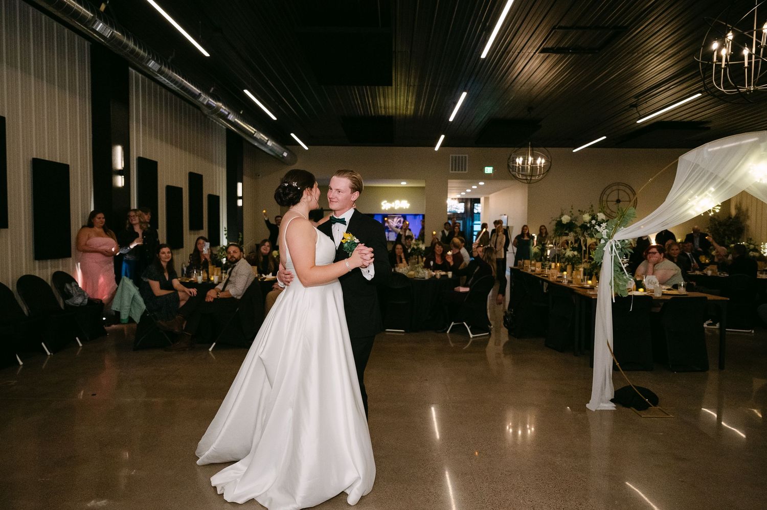 Wedding reception dance floor with guests dancing in a dimly lit venue.