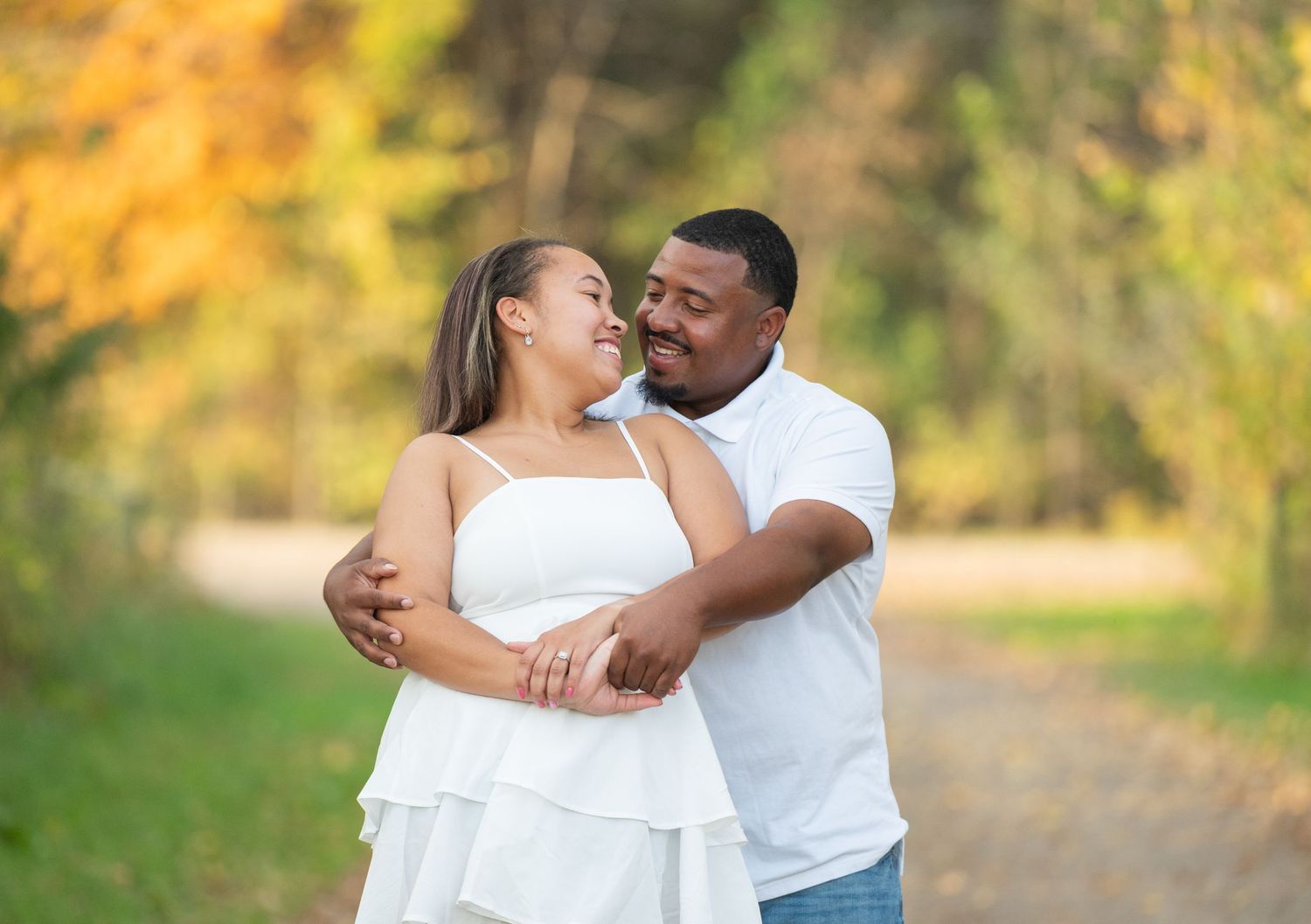 In central Minnesota a couple embraces outdoors during a romantic autumn photoshoot with golden foliage in the background.