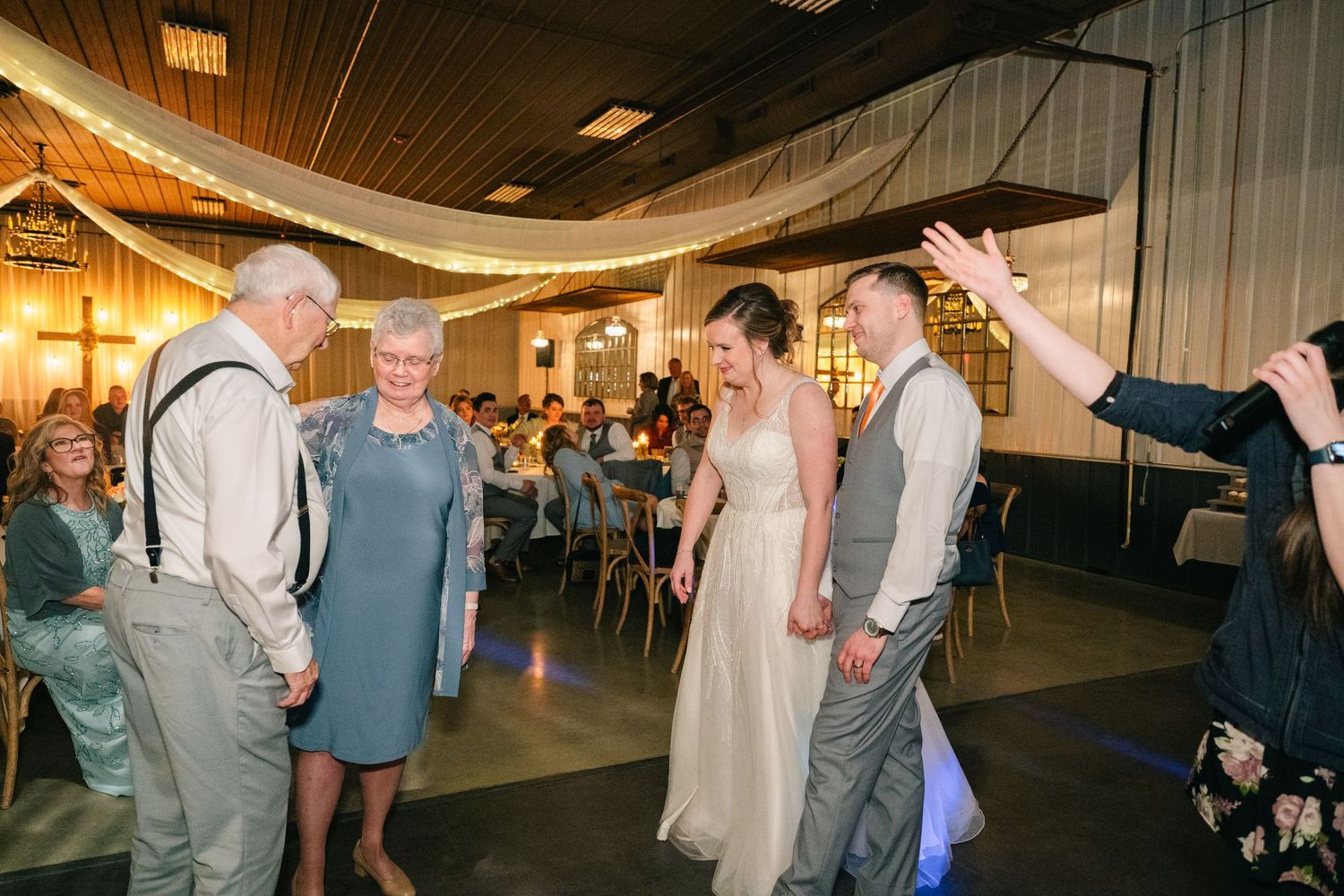 Bride and groom entering wedding reception with grandparents cheering.