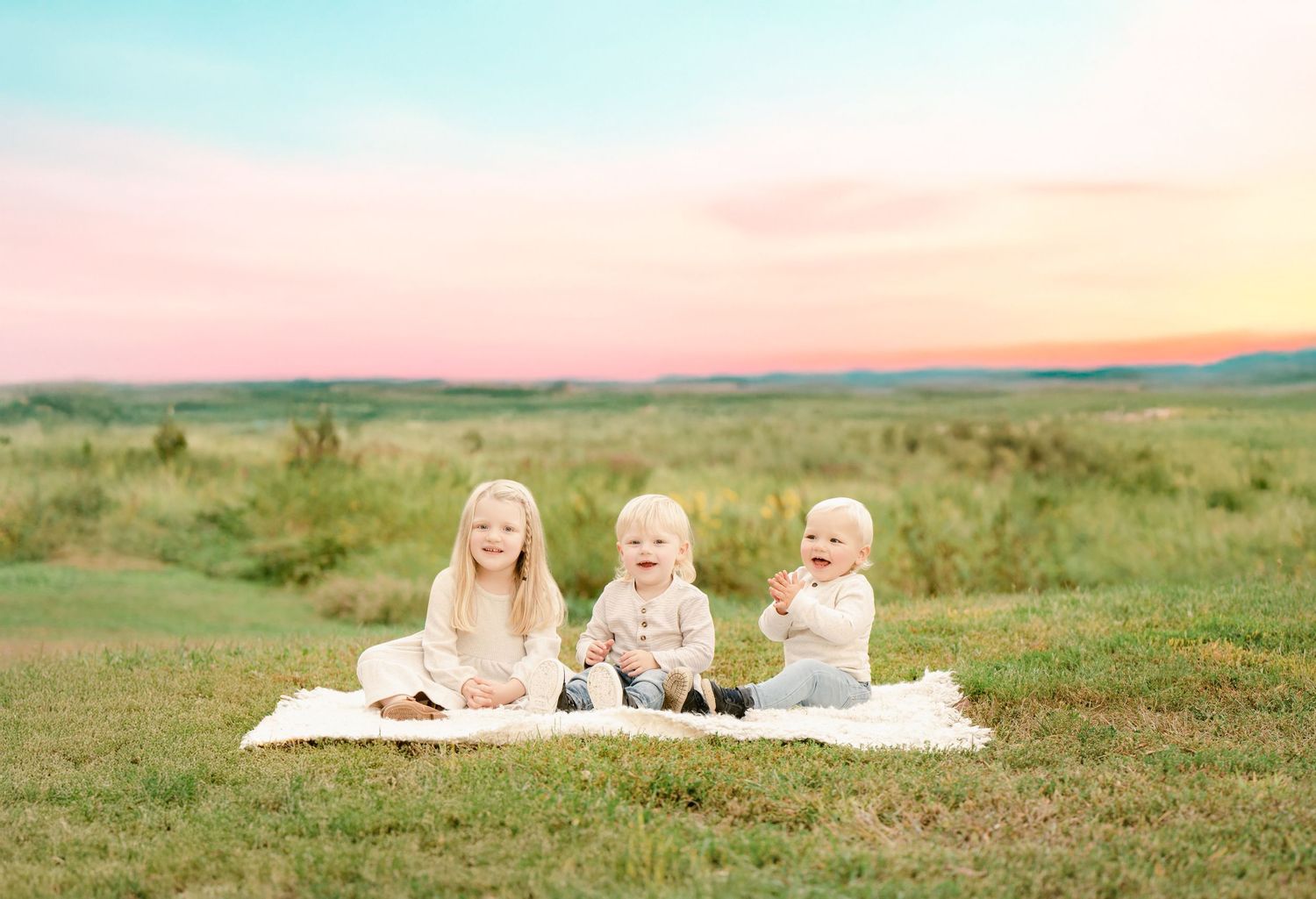 Photos aligned horizontally show children playing on a grassy hillside at sunset with colorful sky in the background.