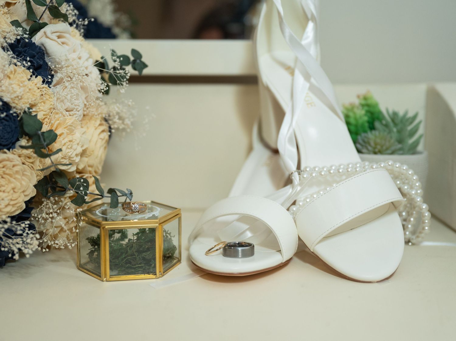 Wedding detail shot showing bridal accessories including shoes and delicate dried flowers on a light surface at Northern Lights near Milaca.