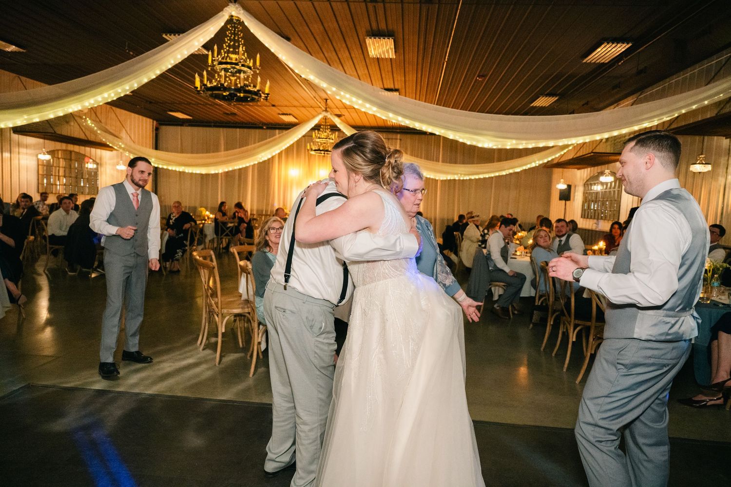 Bride shares a warm hug with a guest on the dance floor during wedding reception celebration.