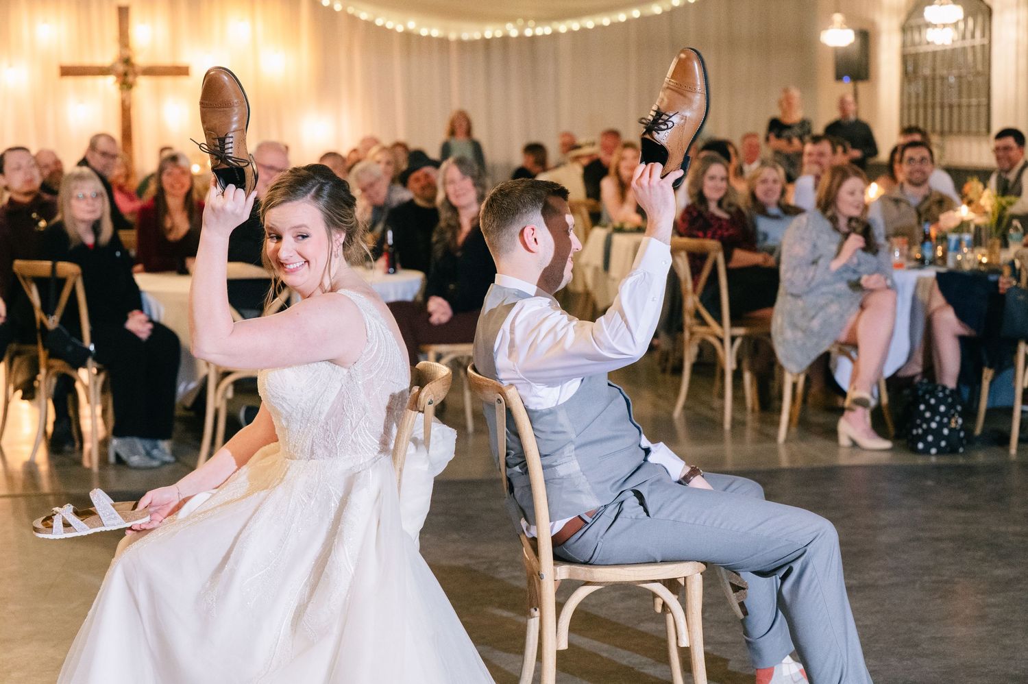 Bride and groom play the shoe game at their wedding reception with guests watching.