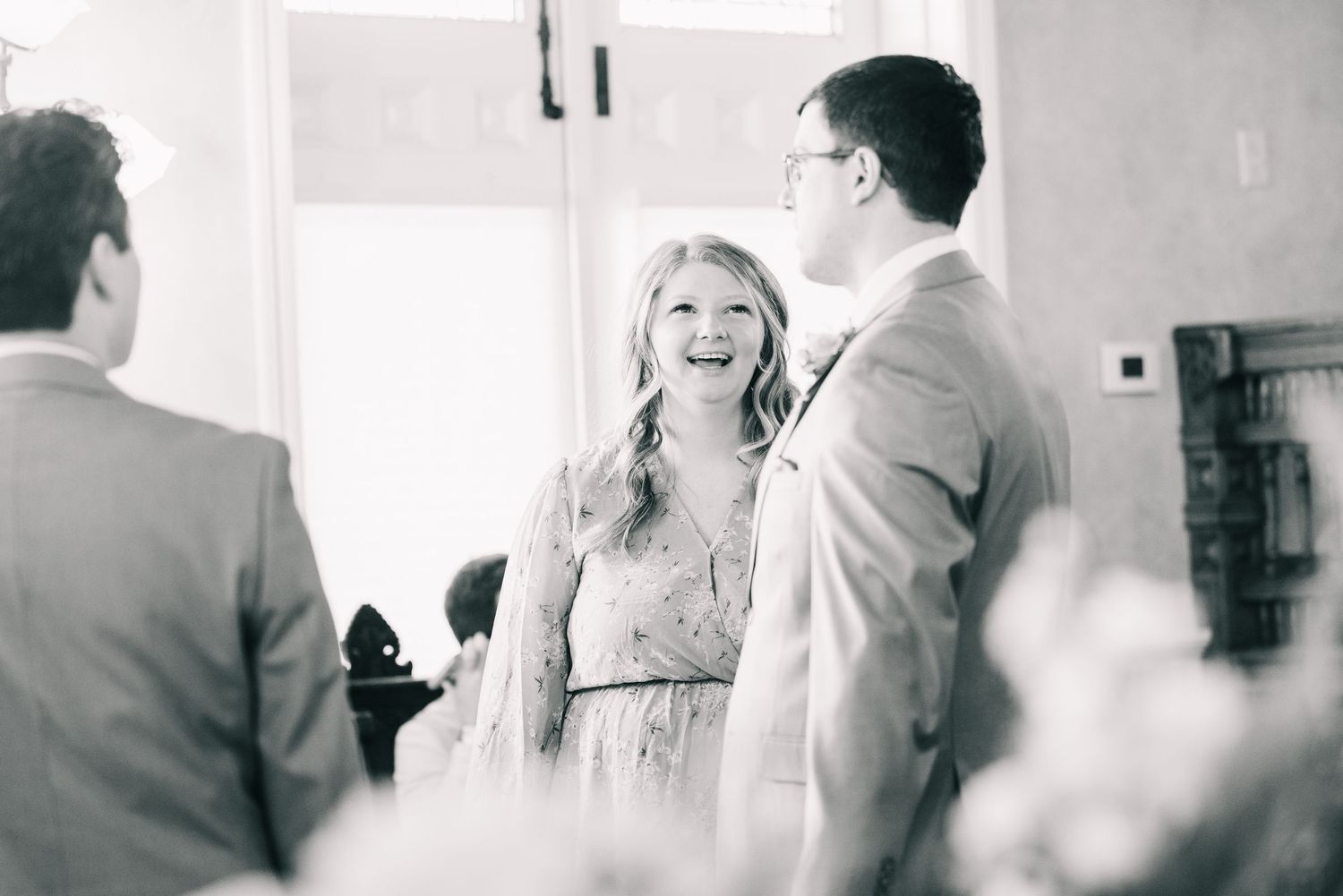 Bride laughing joyfully in black and white photo during wedding ceremony preparations.