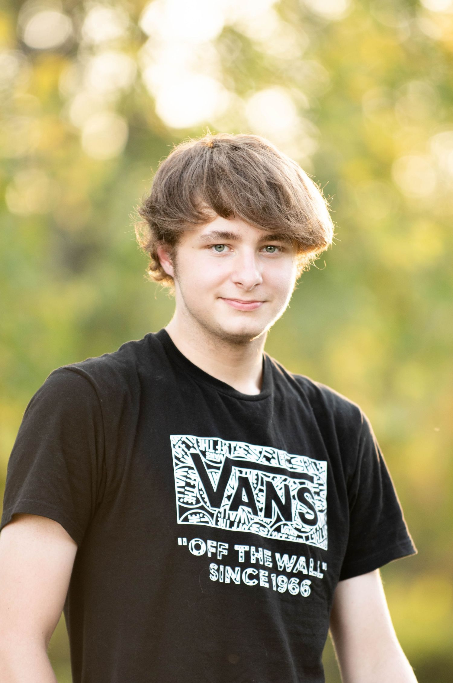 Close-up outdoor portraits with bokeh background and Vans logo t-shirt.
