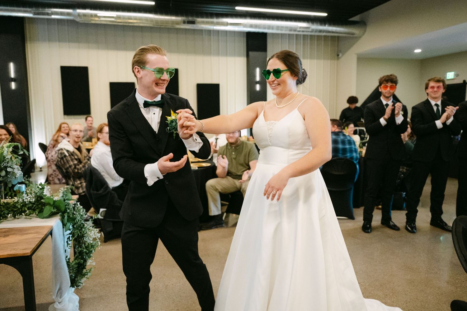 Wedding guests gather around tables at a reception venue with casual conversations and drinks.
