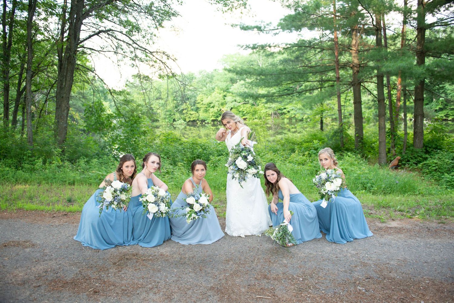 Wedding party in blue dresses posing casually in wooded outdoor setting. Zimmerman MN Weddings