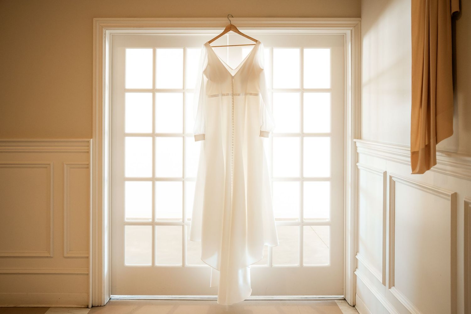 Sunlight streams through multiple tall windows in an elegant white room with ornate crown molding and trim details.