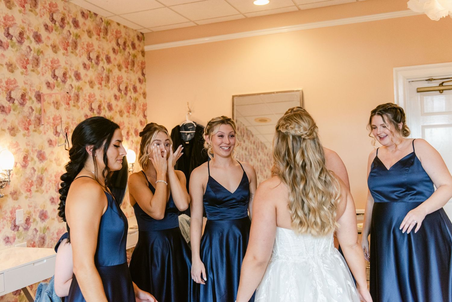 Central MN Wedding Photos | Bridesmaids in navy dresses reacting emotionally to bride in wedding gown.