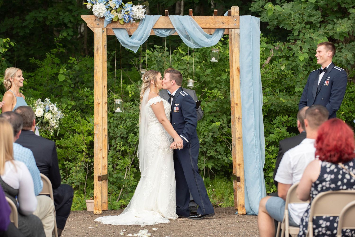 Rustic outdoor wedding ceremony with wooden posts and natural forest backdrop. Zimmerman MN Weddings