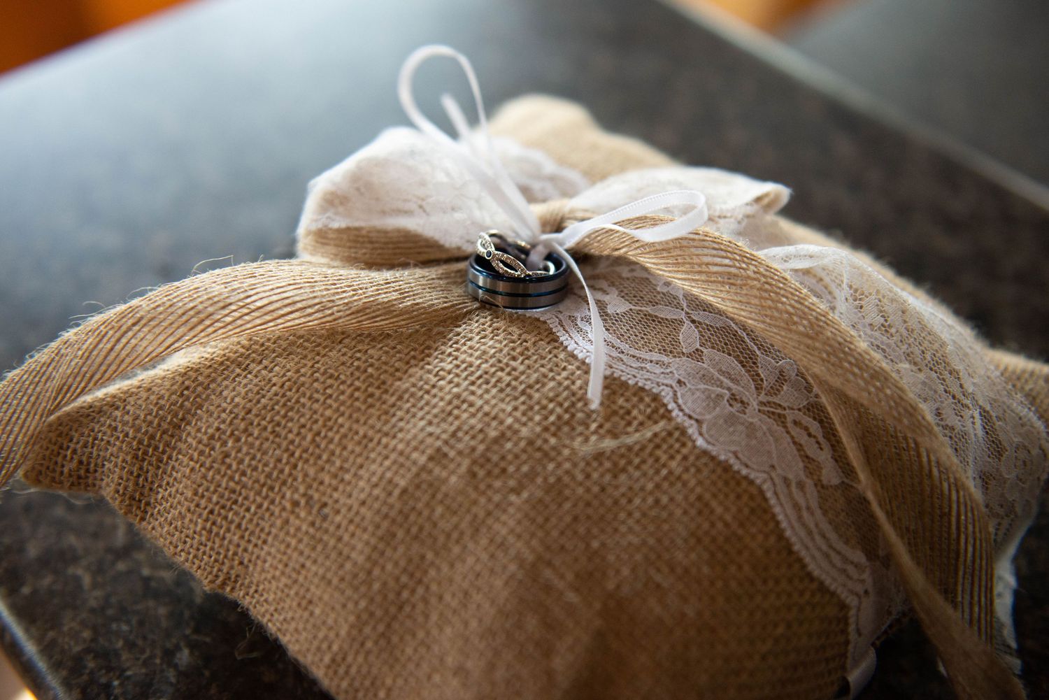 Brown burlap fabric with lace trim and delicate feather details arranged in a rustic decorative style. Zimmerman MN Weddings