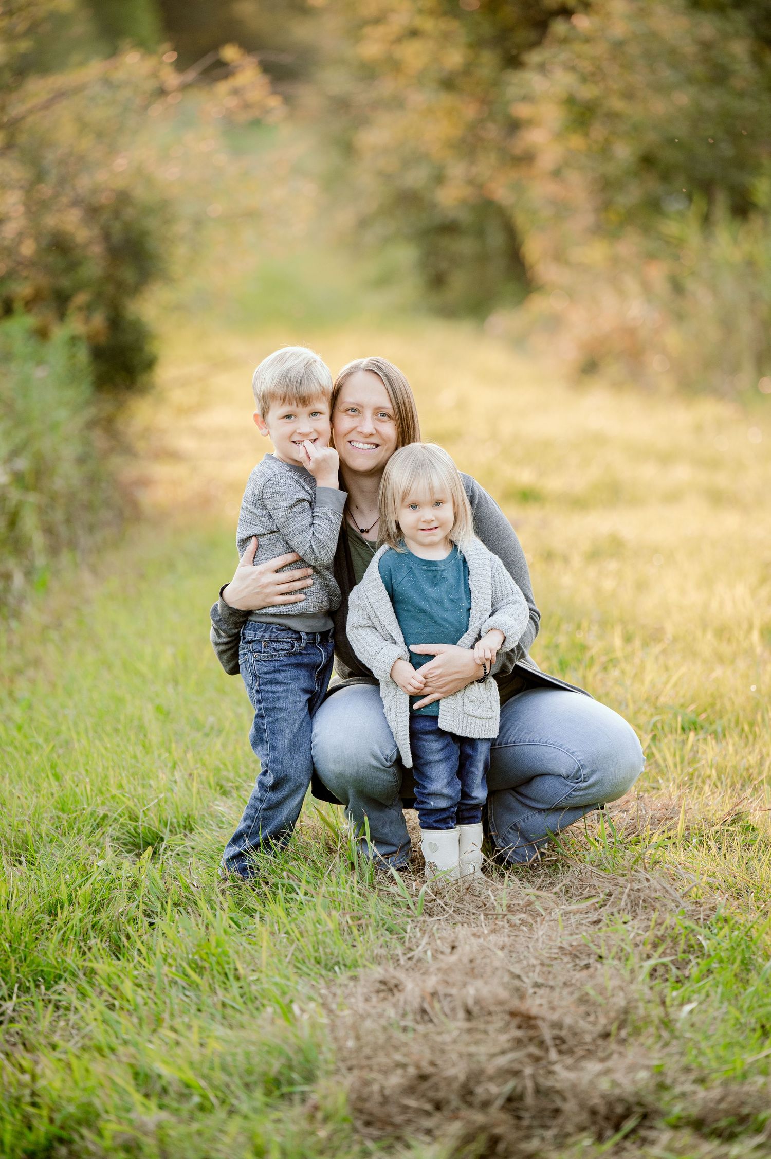 An outdoor portrait in a grassy path with autumn foliage backdrop.