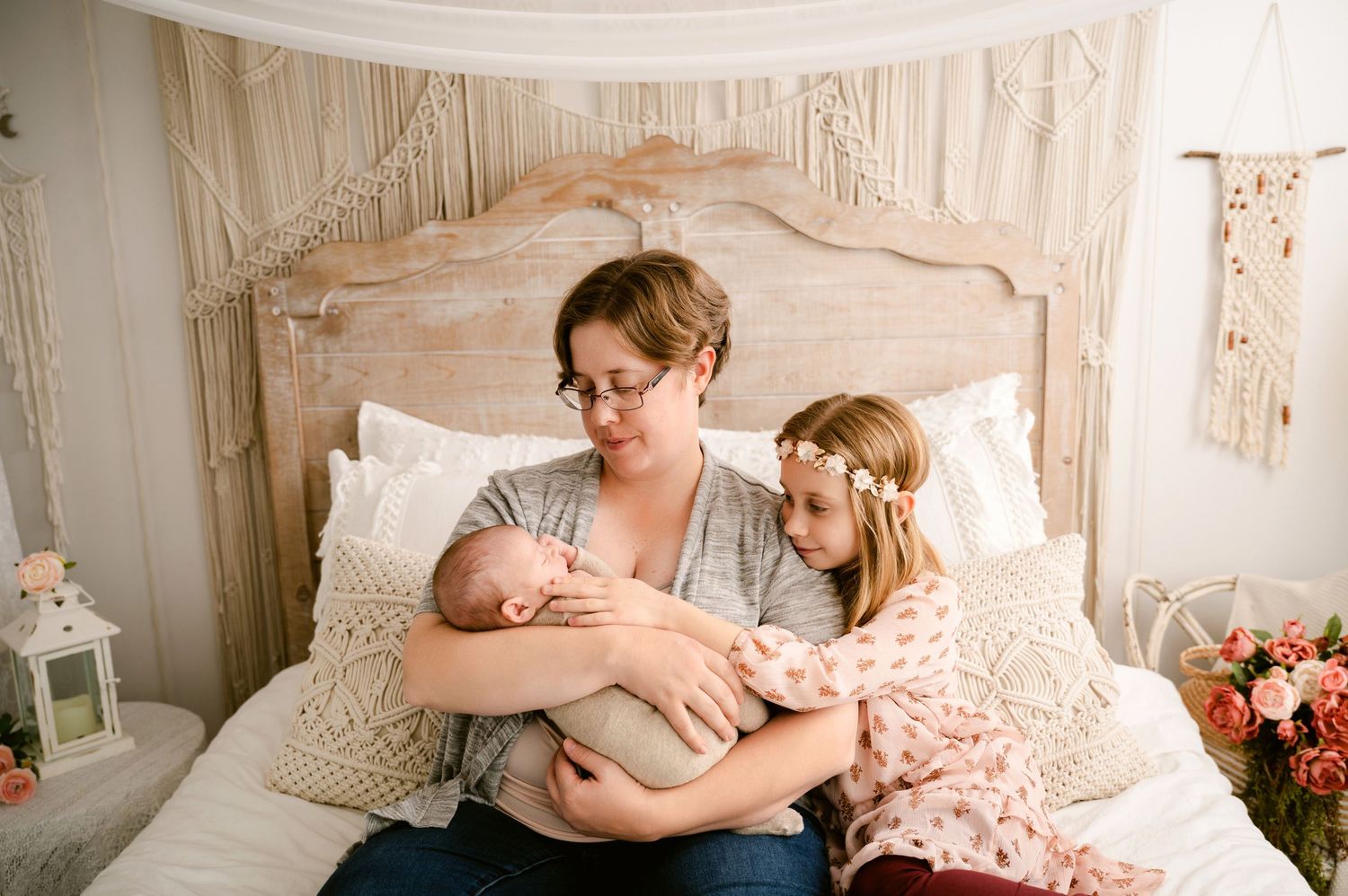 A peaceful moment on a cream-colored bed with family members sharing tender affection with a newborn baby.