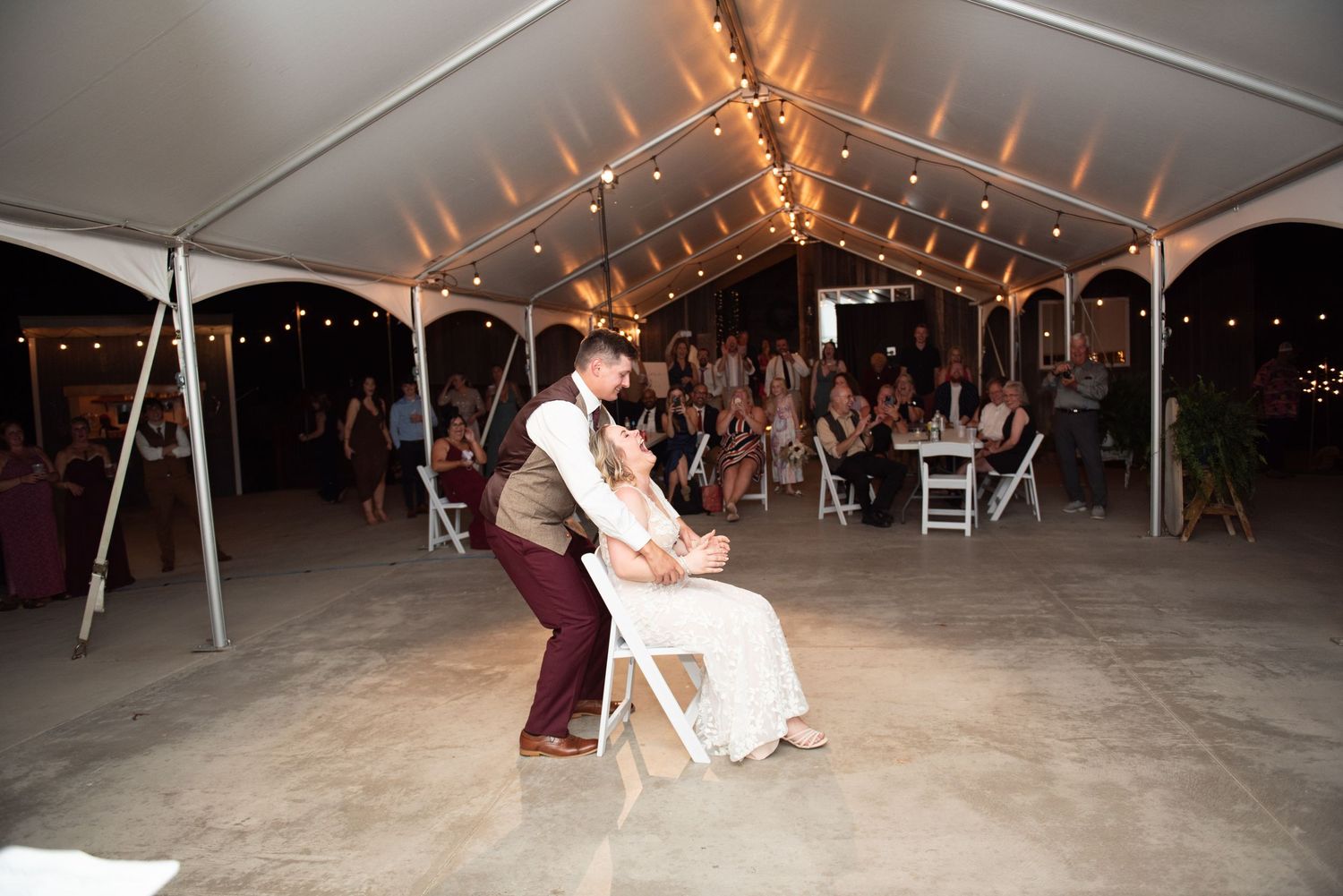 Festive dance floor scene under large white wedding tent during reception.